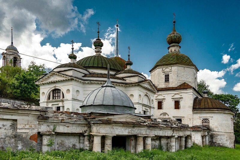 Пятницкая церковь в Старице: белые стены, зелёные купола и портик с колоннами на фоне облачного неба